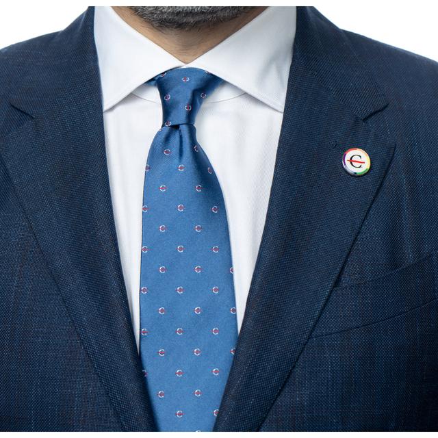 MD Anderson employee wearing a lapel pin featuring black strikethrough 'C' surrounded by a rainbow-colored circle, and blue silk tie with the white strikethrough 'C' pattern.